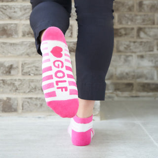 Pink Ladies Golf Trainer Socks come in a 3 pair pack.&nbsp; The cushioned sole and compression fit provide comfort, while the lower ankle cut makes them less visible when worn. These socks feature an attractive stripe on 2 pairs and 1 white plain design all with the word "golf" on the sole. They are made with a soft, stretchy cotton blend fabric for breathability and are suitable for UK sizes 4-7. Made from 85% cotton, 13% polyester, and 2% elastane.