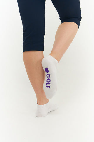 White ladies trainer golf sock, 3 pack with 2 stripped purple pairs and one plain white pair with the word "golf" on the sole, also with a cushioned sole and compression fit. The lower cut around the ankle makes them less visible when worn. Made from a soft, stretchy cotton blend fabric allows breathability. They are suited to UK sizes between 4 and 7. 85% Cotton, 13% Polyester, 2% Elastane.