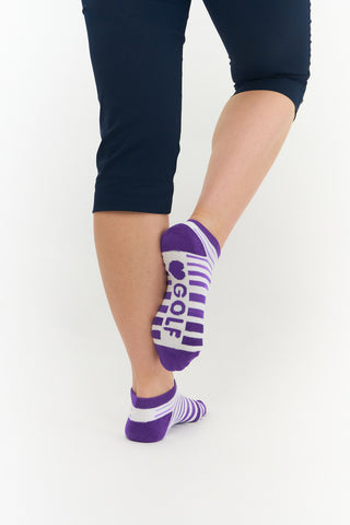 White ladies trainer golf sock, 3 pack with 2 stripped purple pairs and one plain white pair with the word "golf" on the sole, also with a cushioned sole and compression fit. The lower cut around the ankle makes them less visible when worn. Made from a soft, stretchy cotton blend fabric allows breathability. They are suited to UK sizes between 4 and 7. 85% Cotton, 13% Polyester, 2% Elastane.