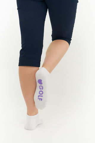 White ladies trainer golf sock, 3 pack with 2 stripped purple, pink and blue pairs and one plain white pair with the word "golf" on the sole, also with a cushioned sole and compression fit. The lower cut around the ankle makes them less visible when worn. Made from a soft, stretchy cotton blend fabric allows breathability. They are suited to UK sizes between 4 and 7. 85% Cotton, 13% Polyester, 2% Elastane.