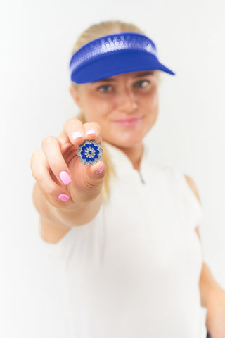 Navy telephone wire crystal ladies golf visor constructed with quick-drying fabrics. The visor comes in a one size fits all. It also features a concealed magnet  in the strong curved peak with a hand enameled lace effect flower shaped golf ball marker. The headband features a soft lined absorbent towel and is crystal-adorned. 