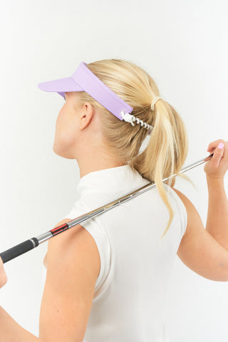 Lilac ladies golf visor constructed with quick-drying fabrics. The visor comes in a one size fits all design with an elasticated cord at the rear to hold it securely in place. It also features a concealed magnet  in peak with a hand enamelled lace golf ball marker attached, making it a lovely golf accessory, golf gift! The headband features a soft lined absorbent towel. 