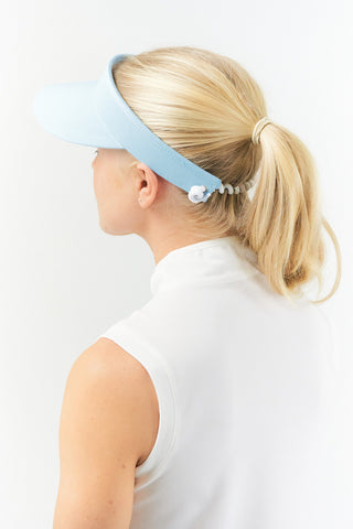 Pale Blue ladies golf visor constructed with quick-drying fabrics. The visor comes in a one size fits all design with an elasticated cord at the rear to hold it securely in place. It also features a concealed magnet  in peak with a hand enamelled lace golf ball marker attached, making it a lovely golf accessory, golf gift! The headband features a soft lined absorbent towel. 