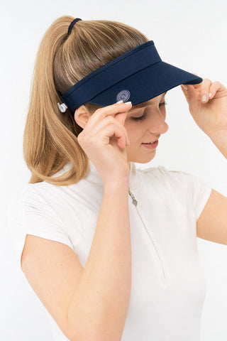 Navy ladies golf visor constructed with quick-drying fabrics. The visor comes in a one size fits all design with an elasticated cord at the rear to hold it securely in place. It also features a concealed magnet  in peak with a hand enamelled lace golf ball marker attached, making it a lovely golf accessory, golf gift! The headband features a soft lined absorbent towel. 